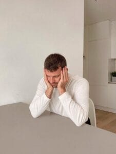 Man with head in hands at a plain table. anxiety disorder that requires more intensive treatment 